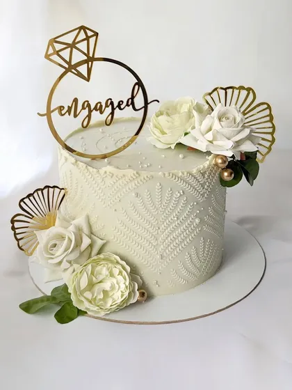 Simple, elegant, and perfect for an engagement party. This single-tier cake features a beautiful white-on-white stencil pattern, accented with fresh white roses and modern gold fans.