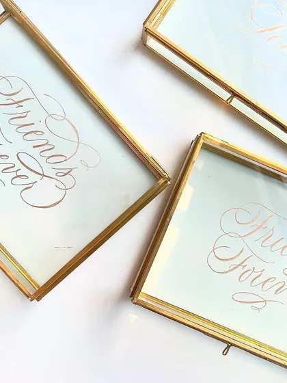 An overhead shot of the engraved "Friends Forever" glass boxes, showing the consistency and detail across multiple pieces for a bulk order.