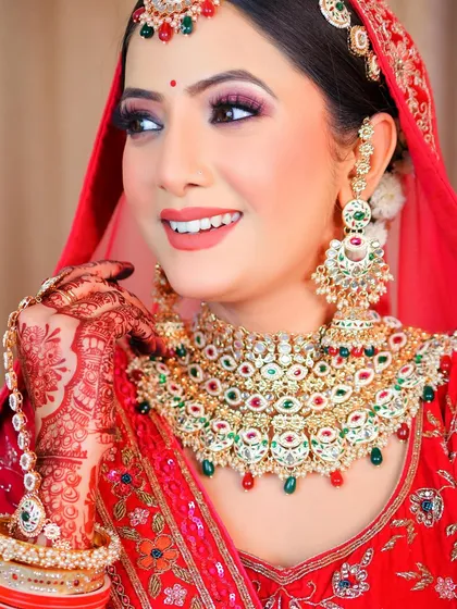 This shot captures the bride's joyful expression, highlighting the vibrant colors of her red lehenga and jewelry.