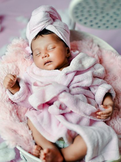 A close-up of the newborn spa day theme, showing the baby's relaxed expression while wearing a tiny bathrobe and towel.