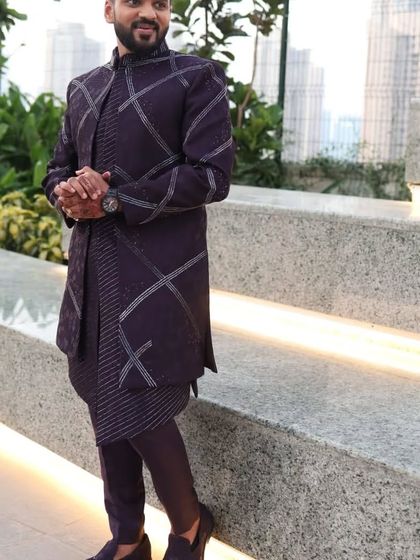 This purple open Indo-Western jacket features a unique geometric pattern created with hand and machine work. It's a bold and stylish choice for a Sangeet or cocktail party.