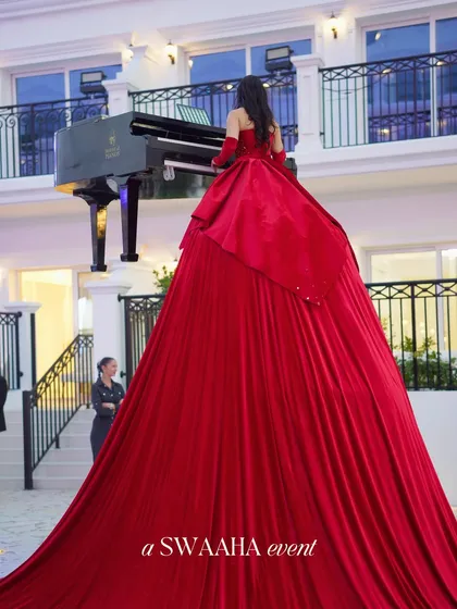 A truly show-stopping moment: a pianist performing on a grand piano while elevated, her voluminous red dress cascading down to the stage.