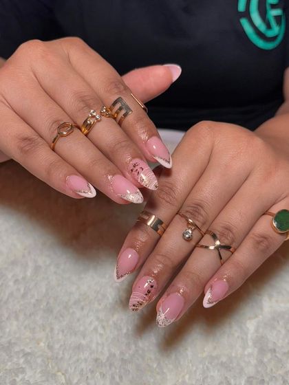 An elegant set with a nude base, a delicate gold and white French tip, and scattered gold flake accents.