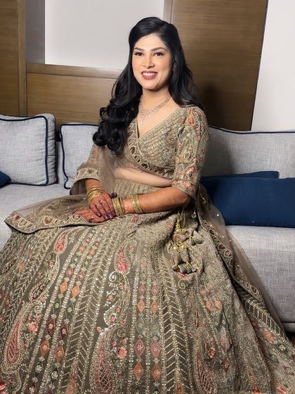 A divine beauty in gold for her Sangeet night. The makeup is kept soft and glowing to complement the heavily embroidered olive and gold lehenga, creating a look of pure elegance.