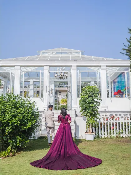 The couple walks hand-in-hand towards a magnificent glasshouse, with the bride's long purple gown trailing behind her. A shot straight out of a modern fairytale.