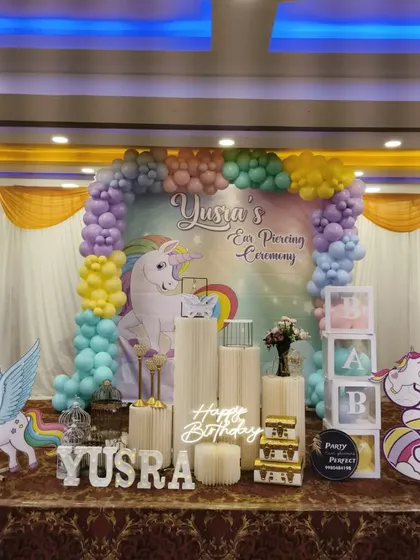 A different view of the unicorn-themed party, showing the full stage with pastel balloons, multiple unicorn cutouts, and elegant white pedestals.
