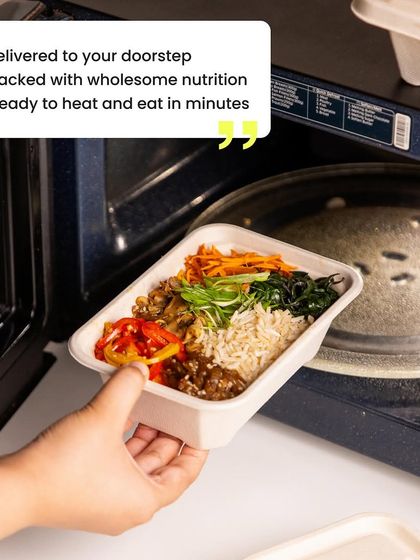 Tired of meal prep? We deliver delicious, healthy meals right to your doorstep. This image shows one of our meal boxes being heated in the microwave, ready to eat in minutes. It's the ultimate convenience.