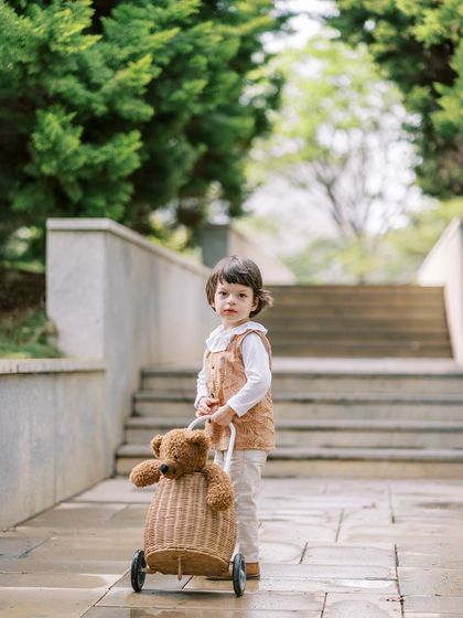 A toddler pulling his teddy bear in a wicker trolley. Props that encourage play are a great way to get natural shots of active little ones.