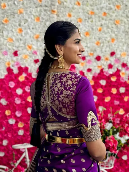 A back view of a rich purple blouse with heavy gold floral embroidery covering the entire back panel. The unique sleeve design adds another layer of custom detail to this bridal look.