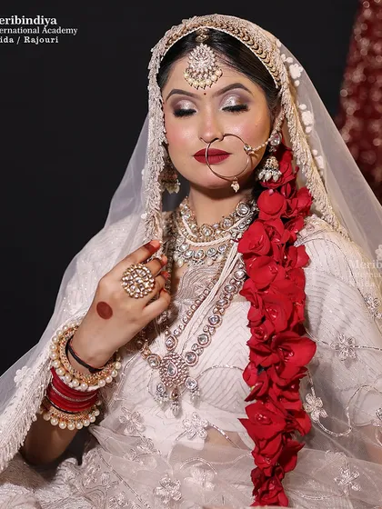 Mastering makeup for lighter-colored outfits is a special skill. This look in a white lehenga features bold red lips and a floral hair braid for a stunning contrast.