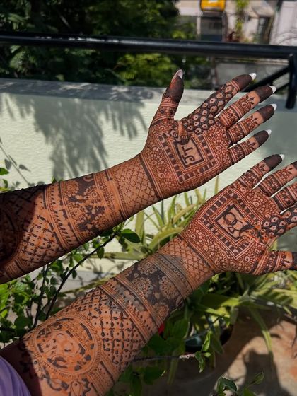 A full view of the front and back of this personalized engagement mehendi. The design is consistent in its themes, with initials, rings, and geometric patterns.