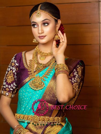 A model wearing our temple jewellery with a turquoise and purple saree. The set includes a choker, long haram, and Vaddanam.