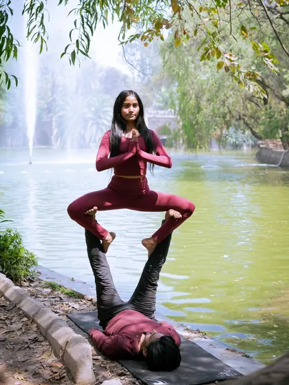The classic acroyoga throne pose, performed with grace and stability by the water in Lodhi Garden.