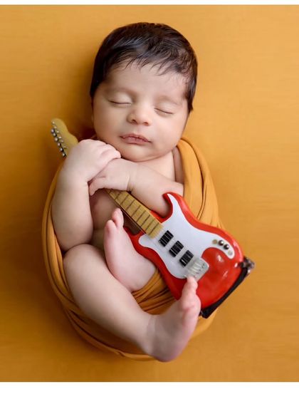 Another angle of the little rockstar, showcasing the classic "tucked-in" pose that newborns love, keeping them secure and sleepy.
