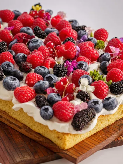 Another beautiful shot of my Vanilla Sheet Cake, showcasing the abundance of fresh berries and edible flowers that make it a visual masterpiece.