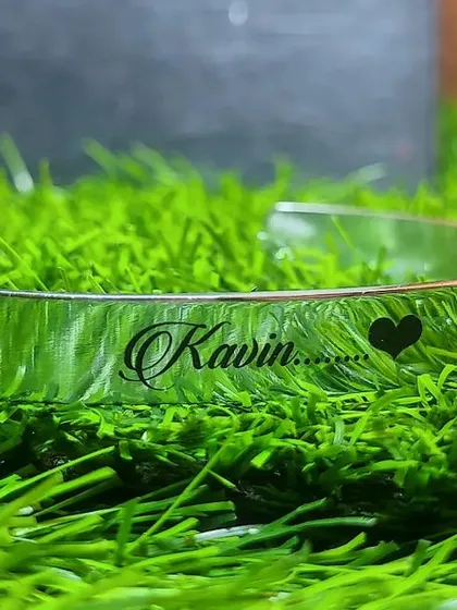A silver cuff with the name 'Kavin' engraved in a script font, complete with a heart symbol. This shows the different font styles I can offer for your custom piece.