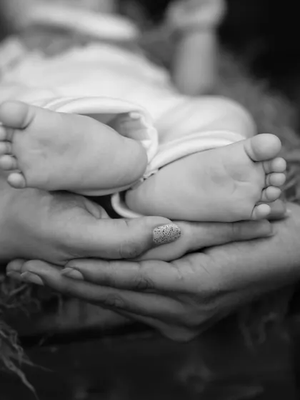 Another beautiful shot focusing on the tiny details. A newborn's feet held lovingly by their parents, a symbol of protection and love.
