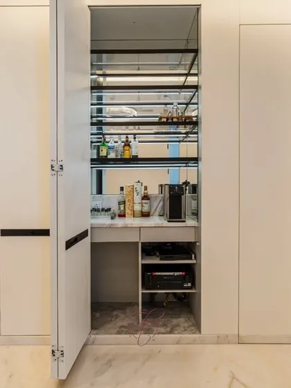 The secret's out. This image reveals the hidden mini-bar, cleverly concealed behind seamless white wall panels. It’s complete with shelving for drinks, glassware, and a coffee machine for the perfect movie break.