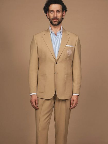 A classic tan suit, perfect for a business-casual environment or warmer weather. The fit is relaxed but structured, with a custom embroidered crest on the patch pocket for a personal touch.