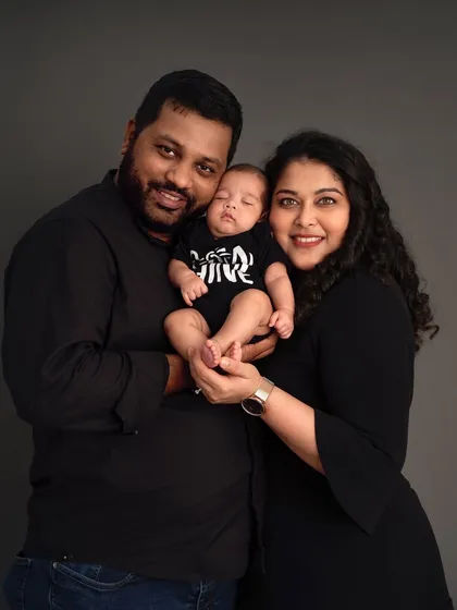 A beautiful family of three posing for a classic newborn portrait. The parents' smiles and the baby's peaceful sleep create a timeless and heartwarming image.