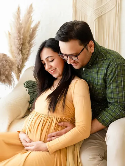 A cozy couple's maternity portrait from a boho-themed session. The earthy tones, soft lighting, and relaxed poses create a warm and intimate atmosphere.