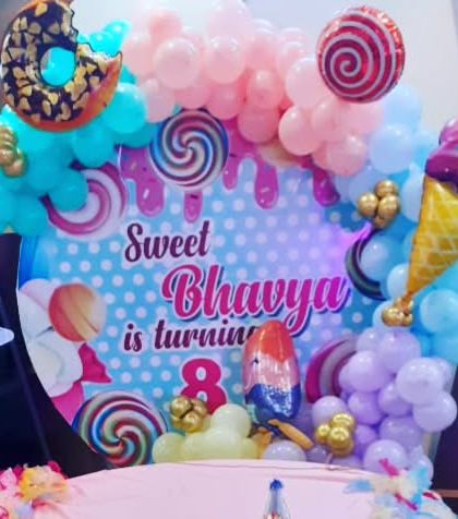 A delicious looking Candyland theme for an 8th birthday. The backdrop is filled with images of sweets, and the balloon garland includes donut and ice cream foil balloons.