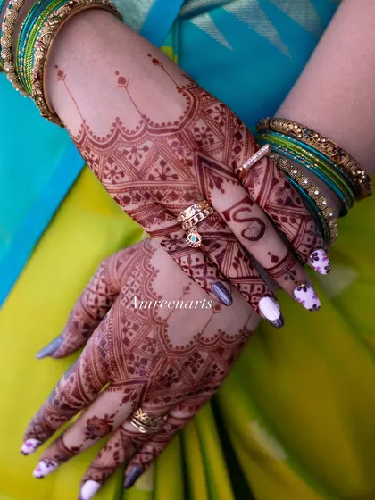 The back of the hands, showing the intricate geometric patterns brought to life by the deep, dark henna stain.