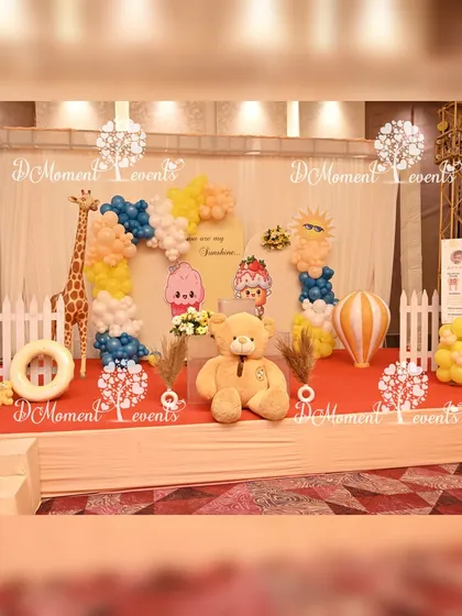 A full view of the stage for the twins' first birthday party. The setup combines elements of a celestial theme with cute animal props like a giraffe and lion, creating a playful and imaginative scene.