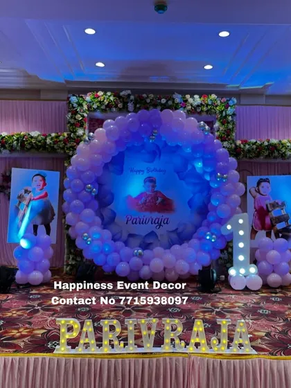 A princess-themed first birthday stage decoration in a hall. This setup uses a large balloon ring as the central element, surrounded by princess cutouts and personalized light-up letters.