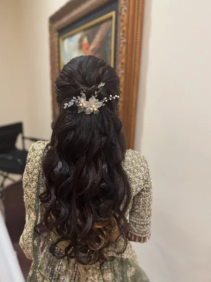 A view of the elegant half-up hairstyle with soft waves created for Haritha's reception. A delicate hair accessory adds a touch of sparkle.