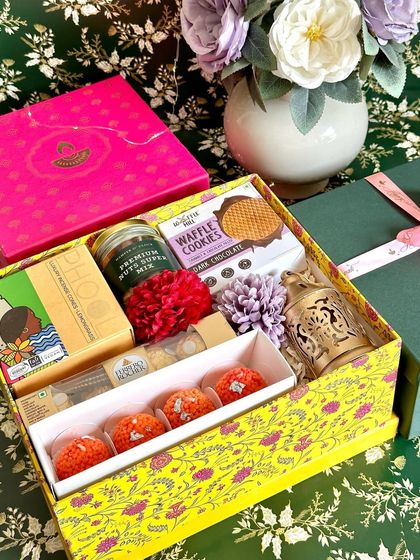 Our 2023 Diwali collection, featuring a yellow printed box filled with tea, cookies, a lantern, and ladoo candles.