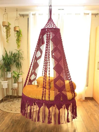 A single seater swing in a deep magenta with a unique diamond-patterned canopy. The yellow cushion creates a bold and beautiful color combination.