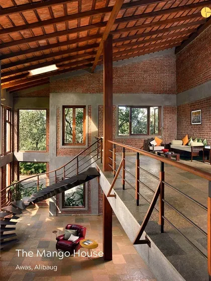 The Mango House in Alibag, a home designed to be both contextual and organic. The double-height living space with its exposed brick and large windows creates a powerful connection to the green landscape outside.