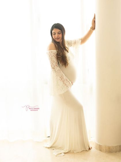 Ethereal and serene. This portrait uses soft, natural window light and a delicate white lace gown to create a timeless and angelic image of the mother-to-be.