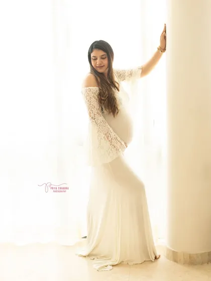 Ethereal and serene. This portrait uses soft, natural window light and a delicate white lace gown to create a timeless and angelic image of the mother-to-be.