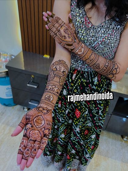 A client showing off her full-arm traditional mehndi. The design features elephants and intricate architectural patterns, creating a grand and royal look.
