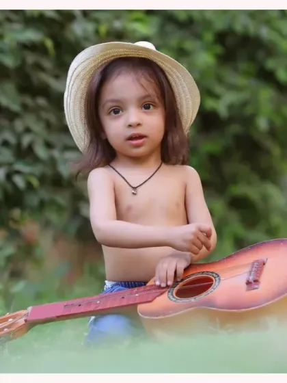 A young boy with his guitar in a natural, green setting. The soft, diffused light of an outdoor shoot is perfect for creating artistic portraits.