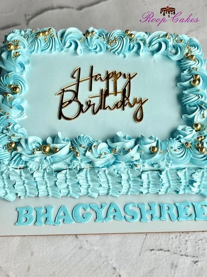 A beautiful blue sheet cake with decorative piping and a golden 'Happy Birthday' topper, perfect for any celebration.