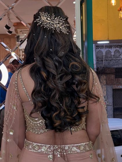 The back of her hairstyle, showing off the long, perfect curls and a stunning, intricate hairpiece that adds a touch of sparkle.