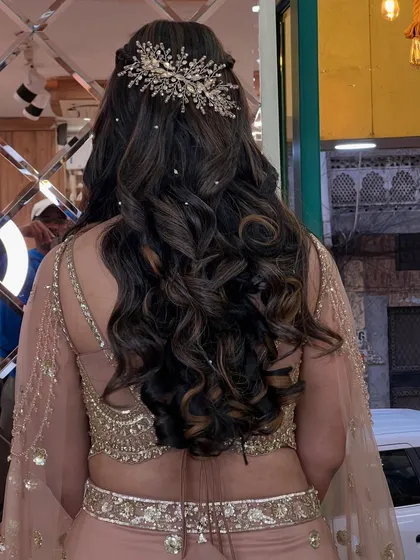 The back of her hairstyle, showing off the long, perfect curls and a stunning, intricate hairpiece that adds a touch of sparkle.