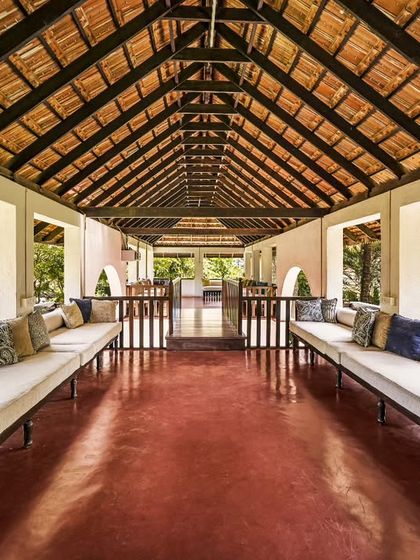 A comfortable lounge area in an open-air veranda, with long cushioned benches overlooking the gardens. It's a perfect place for guests to gather, talk, or simply relax.