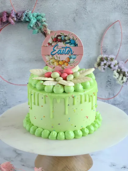 Hop into Easter with our festive green drip cake. Topped with an Easter-themed disc and colorful decorations, it's a cheerful addition to your holiday table.