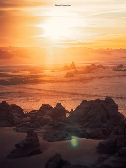 The desert landscape of Hegra, Saudi Arabia, at sunrise. The warm light illuminates the ancient rock formations, creating a scene that feels like another world.