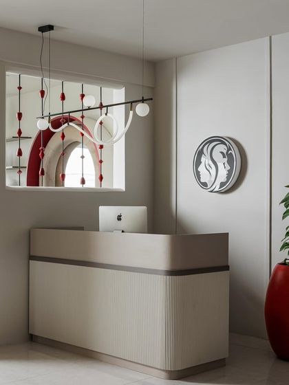 The reception desk features clean, curved lines and a minimalist design, set against a backdrop of subtle wall paneling. The custom brand logo and artistic light fixture immediately establish the salon's chic, modern identity.