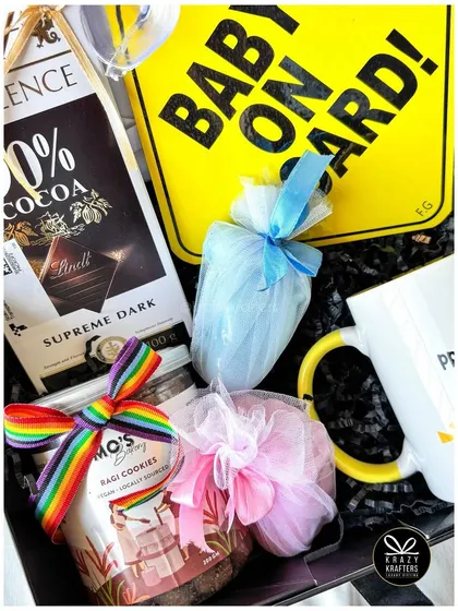 A detail shot of the treats inside a pregnancy announcement hamper, including gourmet cookies and chocolates wrapped in colorful tulle.