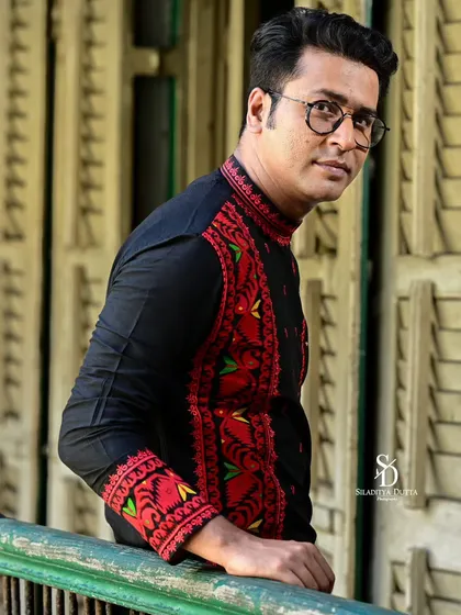 A close-up portrait of Anirban looking towards the camera. The natural light from the side creates a gentle and flattering look, focusing on his expression.