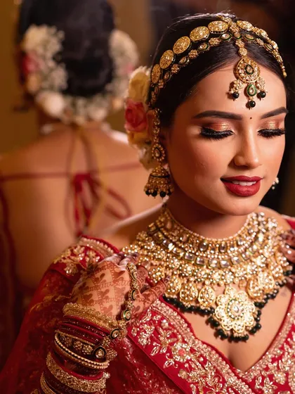 A close-up showcasing the intricate details of the bridal look. The combination of a bold red lip, shimmering gold eyeshadow, and perfectly placed jewelry creates a timeless and regal aesthetic.