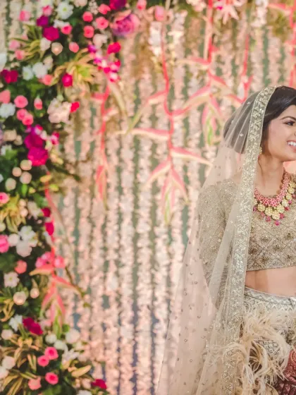A candid shot of the bride, beautifully framed by a floral arch. This image highlights her joyful expression and the stunning wedding decor.