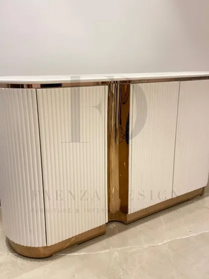 A beautiful custom console designed for a foyer. This piece features a curved, fluted body in a white Duco finish, accented with a rose-gold metallic finish, creating a warm and welcoming first impression.