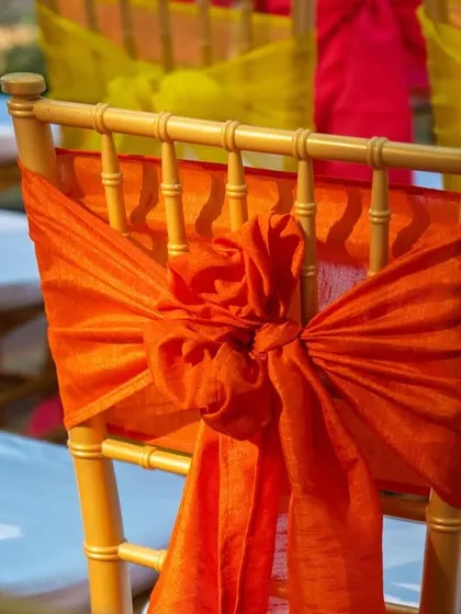 Detail of a chair decorated with a beautifully tied orange sash, showing how small details contribute to the overall carnival theme.